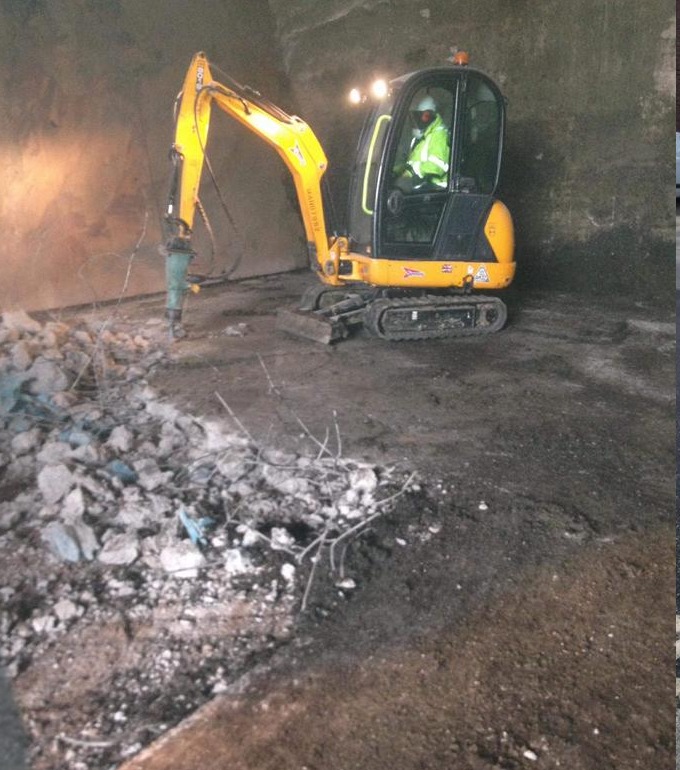 All Site Services excavator breaking up a concrete surface